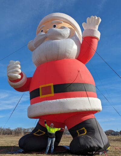 Showing a worker next to a giant inflatable Santa display at the Magical Lights of Lincoln family produced Christmas lights show at the Lancaster Event Center